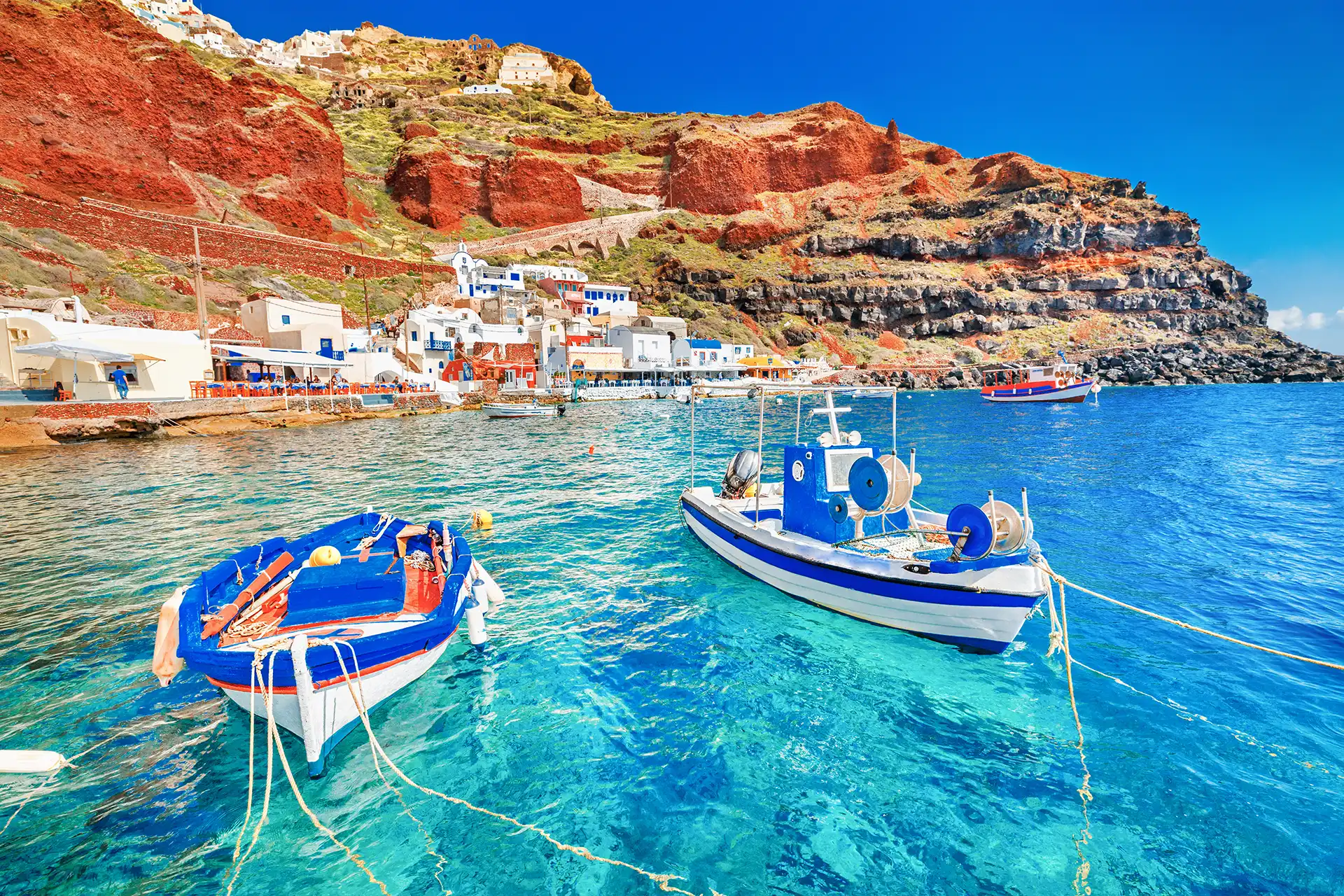 Greece. Breathtaking beautiful landscape of two fishing boats anchored to quay in fascinating blue water at the amazing old port panorama in Oia Ia village